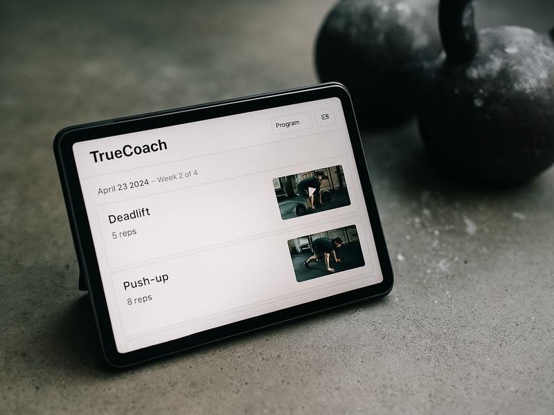 TrueCoach app interface showing workout programs and video demonstrations for online coaching